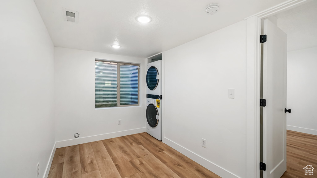 Laundry room with stacked washer / dryer and light wood-style floors