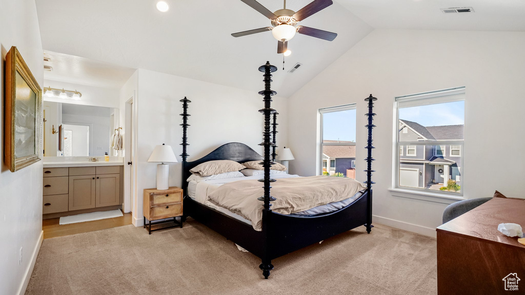 Bedroom with lofted ceiling, light carpet, connected bathroom, and a ceiling fan