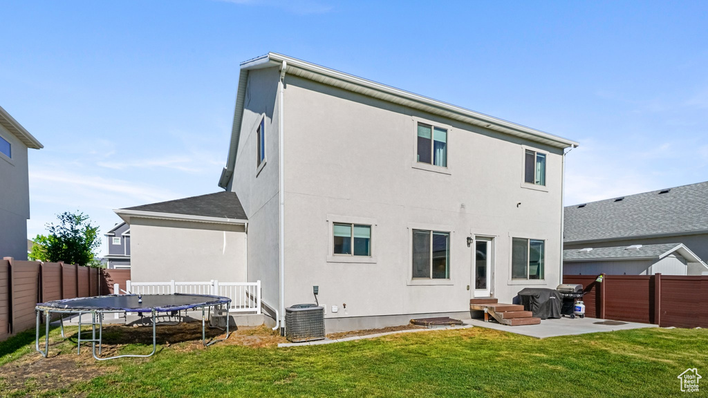 Back of house with a trampoline, a fenced backyard, and stucco siding