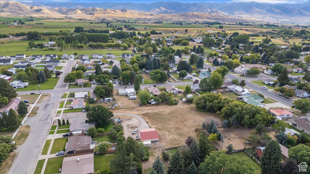 Aerial view of property and surrounding area featuring a mountain backdrop and nearby suburban area