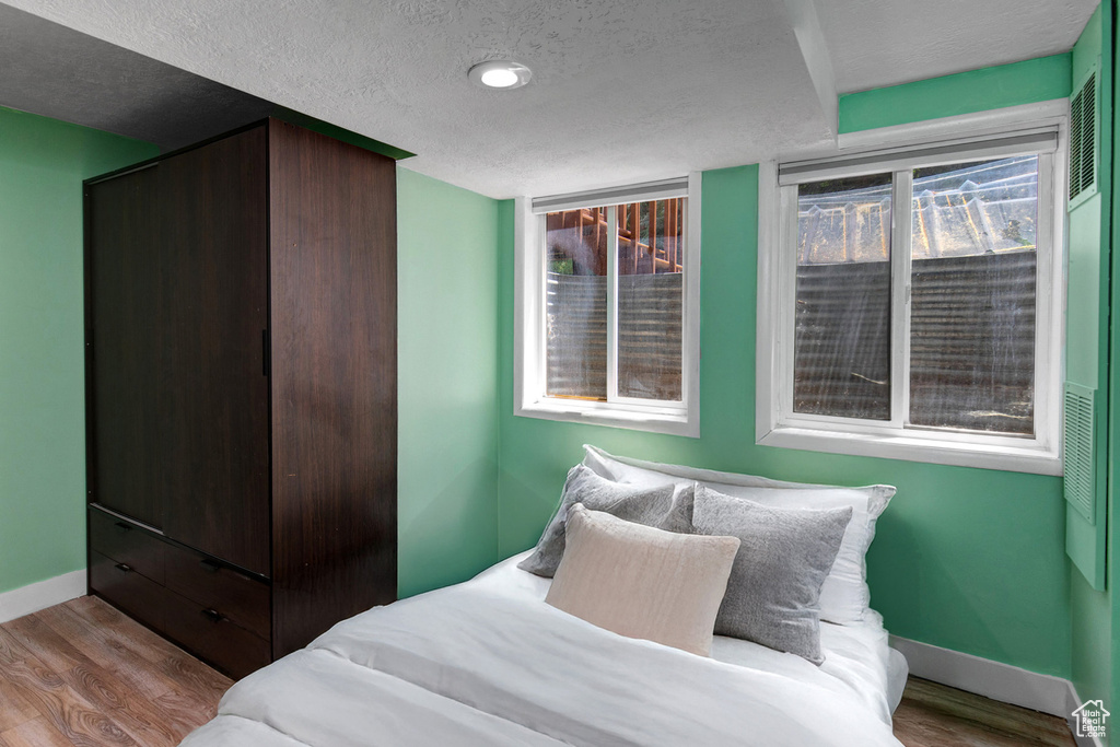 Bedroom with wood finished floors and a textured ceiling