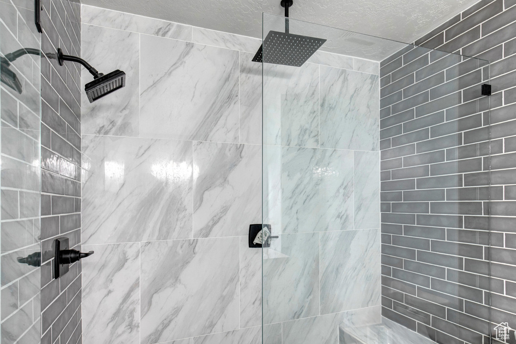 Bathroom with a tile shower and a textured ceiling