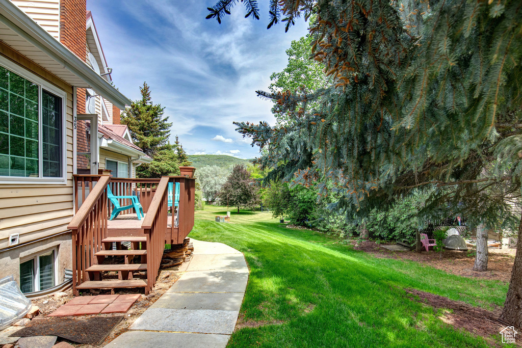 View of grassy yard featuring a deck with mountain view