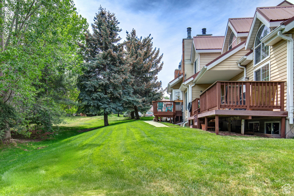 View of grassy yard with a wooden deck
