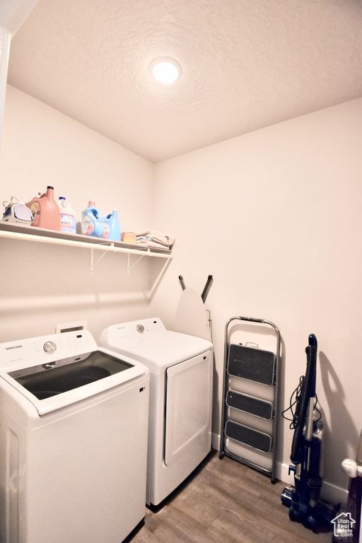 Laundry room with wood finished floors and washer and dryer