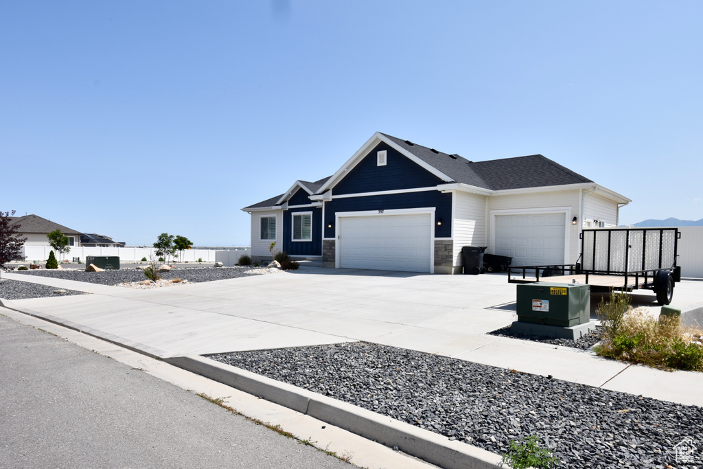 View of front of home with a garage, driveway, and stone siding