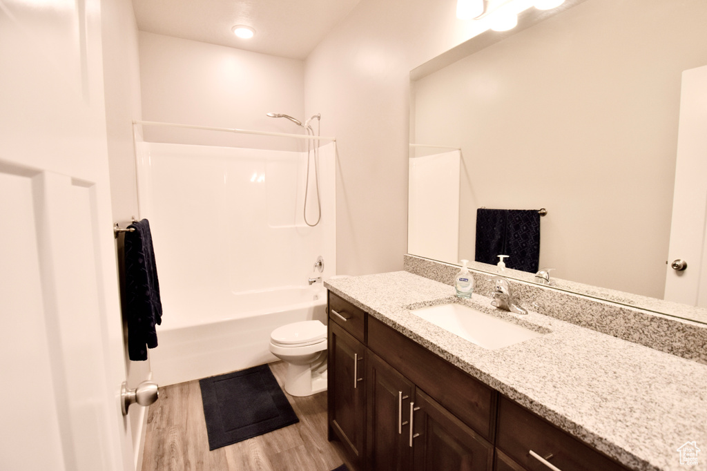 Full bathroom featuring vanity, toilet, washtub / shower combination, and wood finished floors