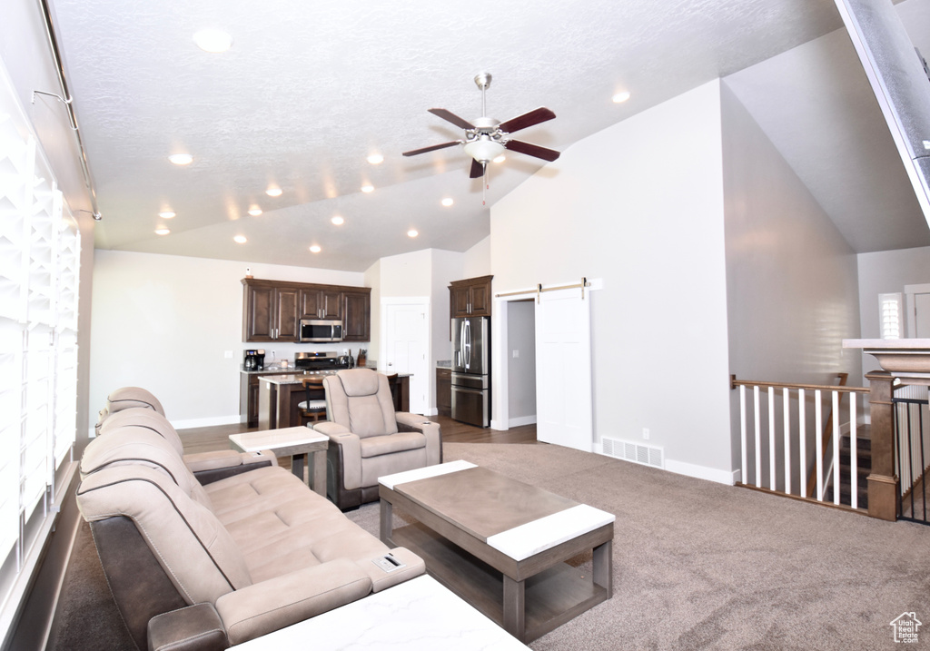 Living area featuring ceiling fan, a barn door, vaulted ceiling, recessed lighting, and baseboards