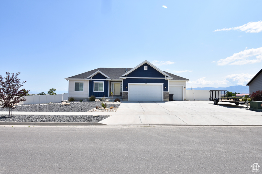 View of front of home featuring an attached garage, concrete driveway, and stone siding