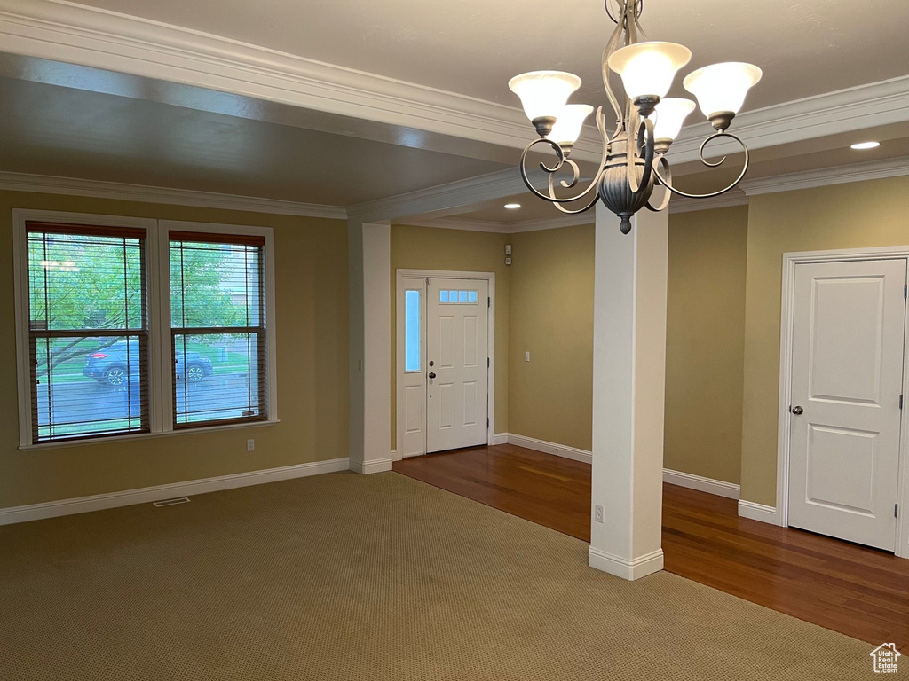 Carpeted entrance foyer with a chandelier, ornamental molding, and recessed lighting