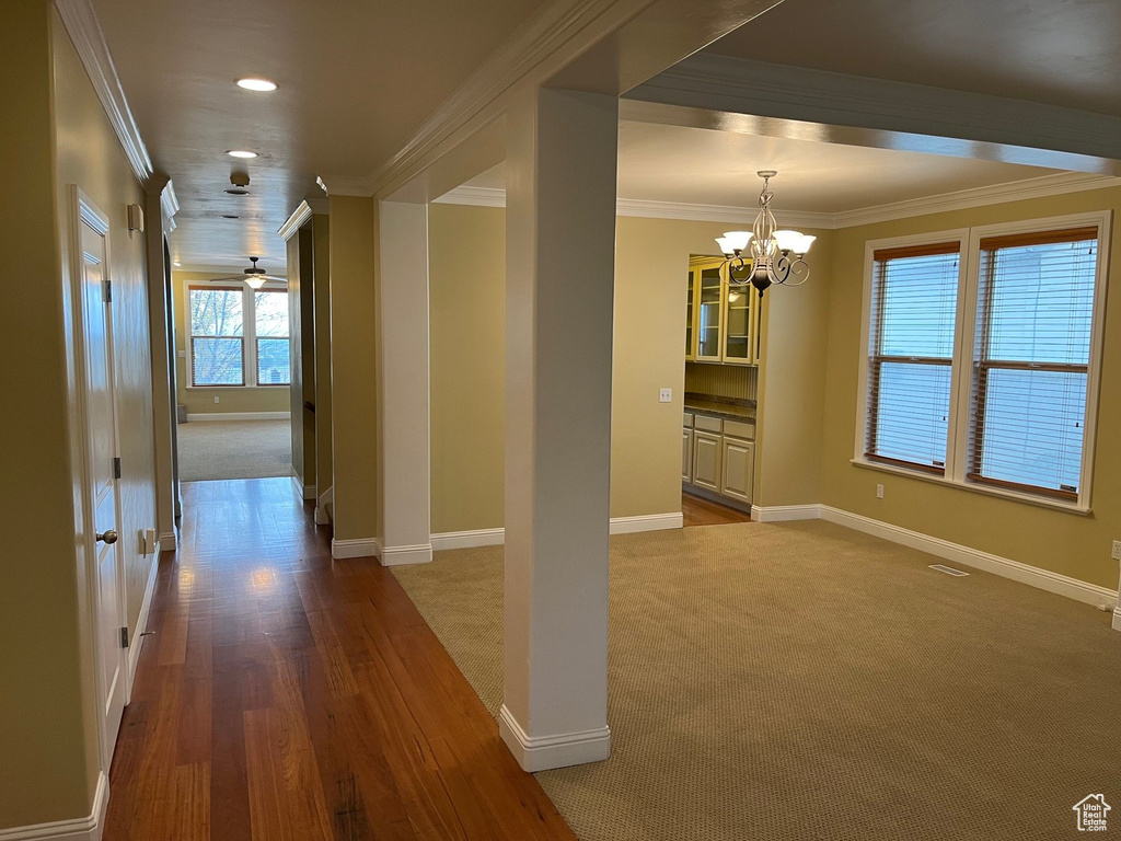Hall featuring a chandelier, ornamental molding, carpet flooring, recessed lighting, and wood finished floors