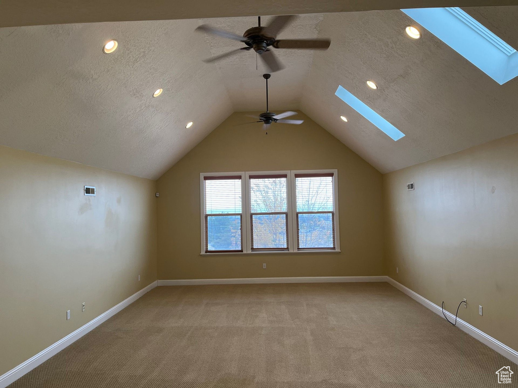 Additional living space featuring ceiling fan, a skylight, light carpet, lofted ceiling, and recessed lighting