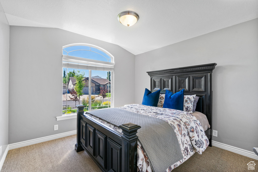 Carpeted bedroom featuring vaulted ceiling and baseboards