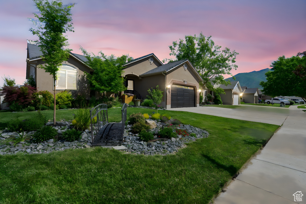 View of front of home with stucco siding, an attached garage, a front lawn, and concrete driveway