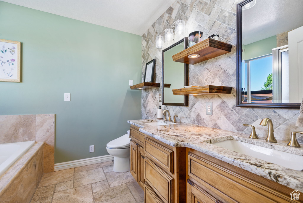 Bathroom featuring double vanity, a garden tub, stone tile flooring, and decorative backsplash