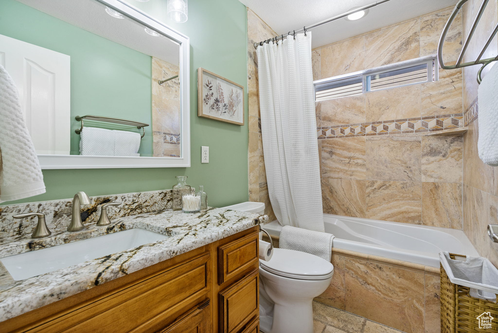 Full bath with vanity, tiled shower / bath combo, and stone finish floors