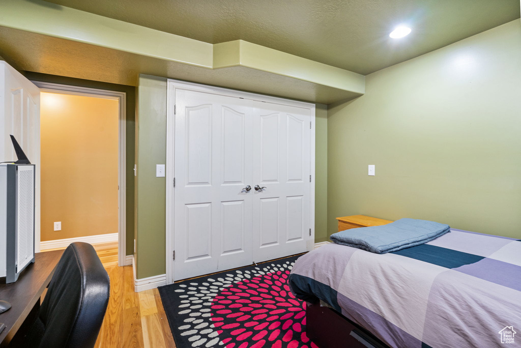 Bedroom with light wood-type flooring, recessed lighting, and a closet