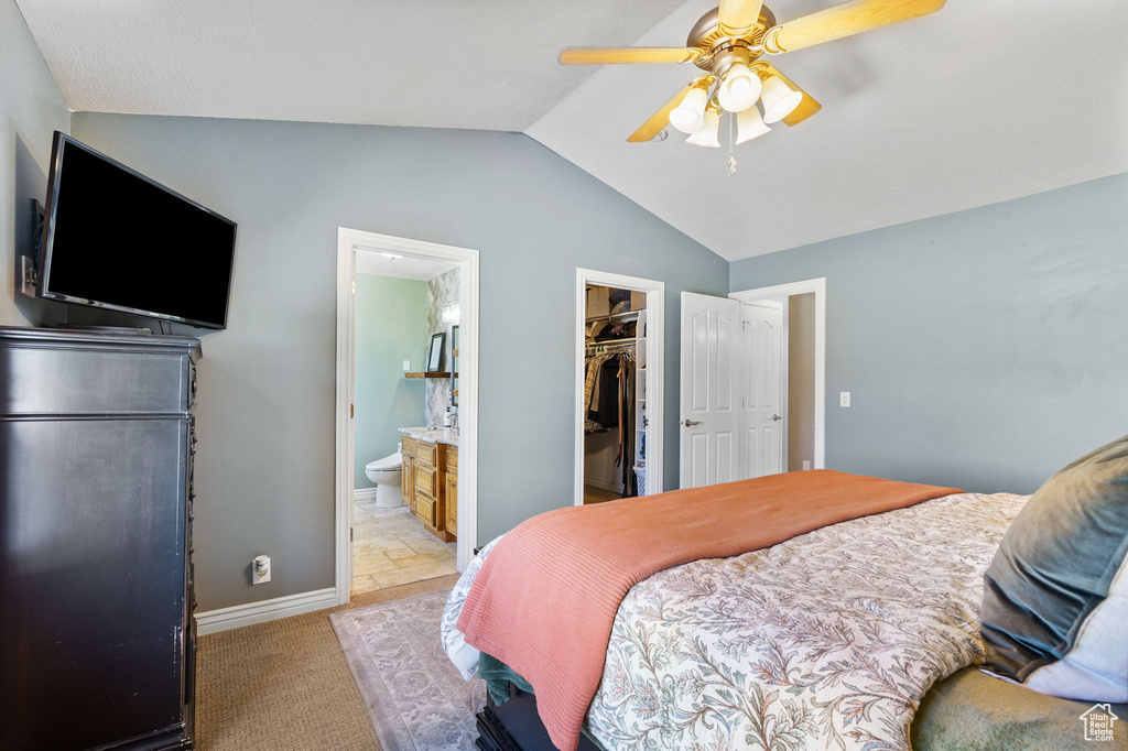 Bedroom with vaulted ceiling, a spacious closet, a closet, ensuite bathroom, and a ceiling fan