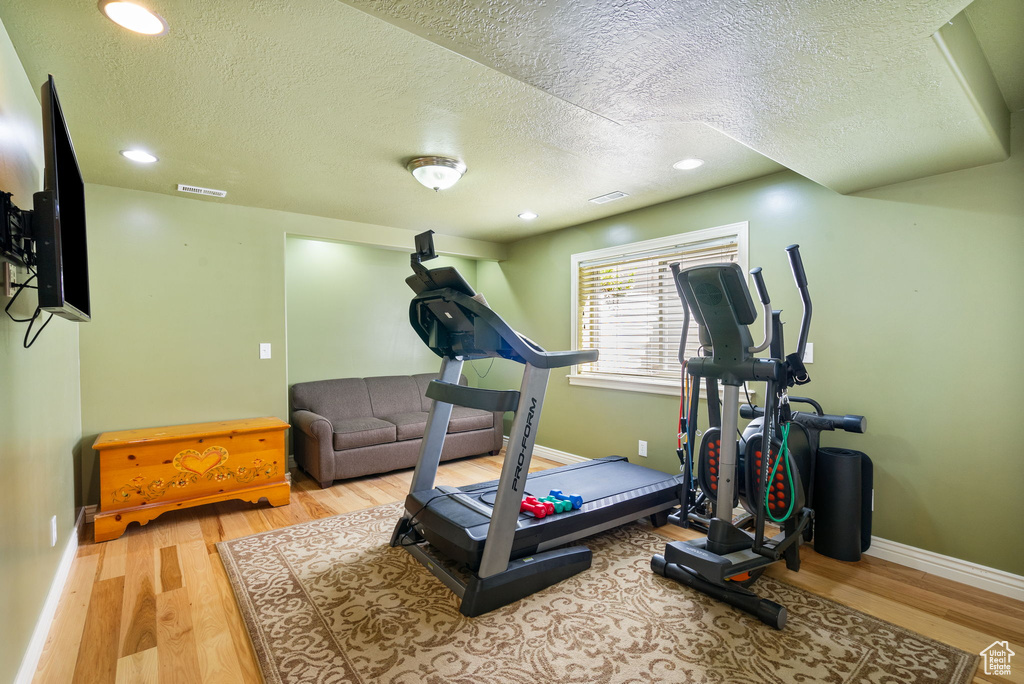 Exercise area featuring a textured ceiling, wood finished floors, and recessed lighting