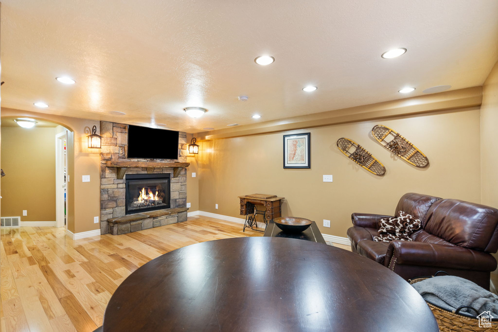 Living area with light wood-type flooring, recessed lighting, a stone fireplace, and arched walkways