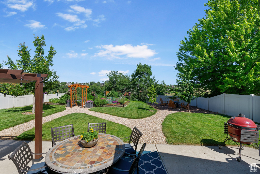 Fenced backyard with a patio, outdoor dining area, a garden, and a pergola