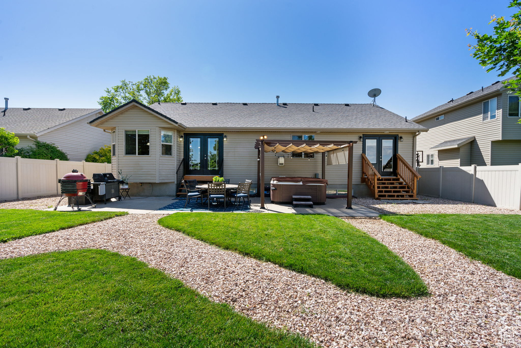 Back of house with french doors, a hot tub, a fenced backyard, and a patio area
