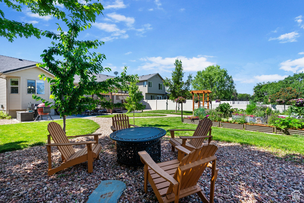 View of yard featuring an outdoor fire pit, a patio, a garden, and a residential view