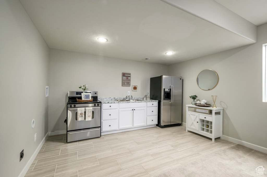 Kitchen with stainless steel appliances, baseboards, a sink, white cabinetry, and recessed lighting