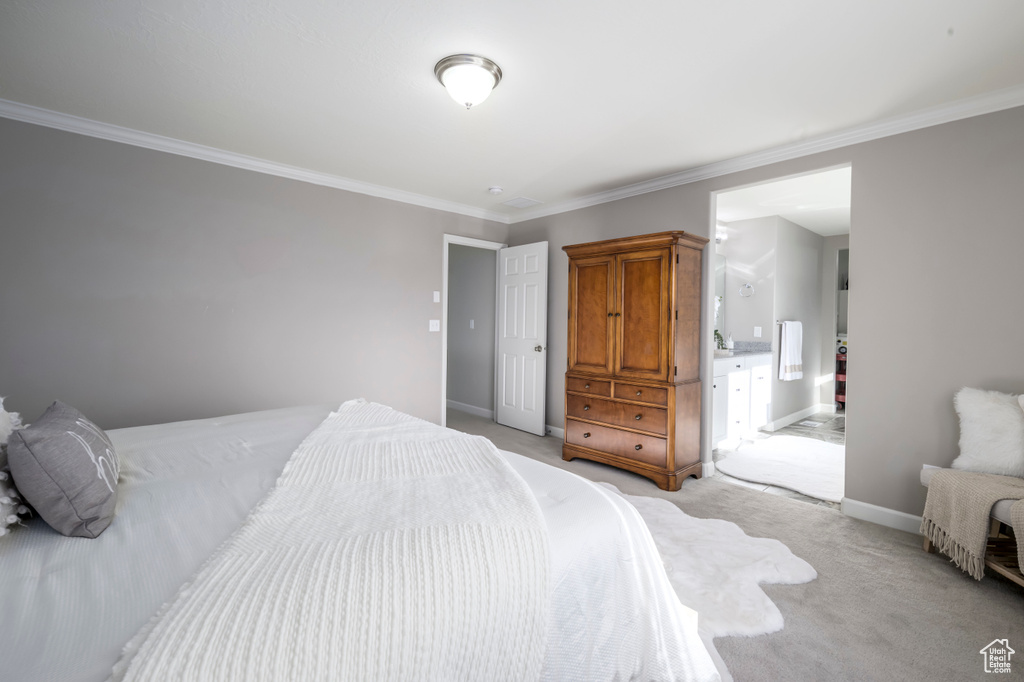 Bedroom with light colored carpet, ornamental molding, baseboards, and connected bathroom