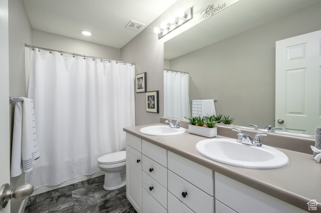 Full bath with toilet, double vanity, and shower / bath combo