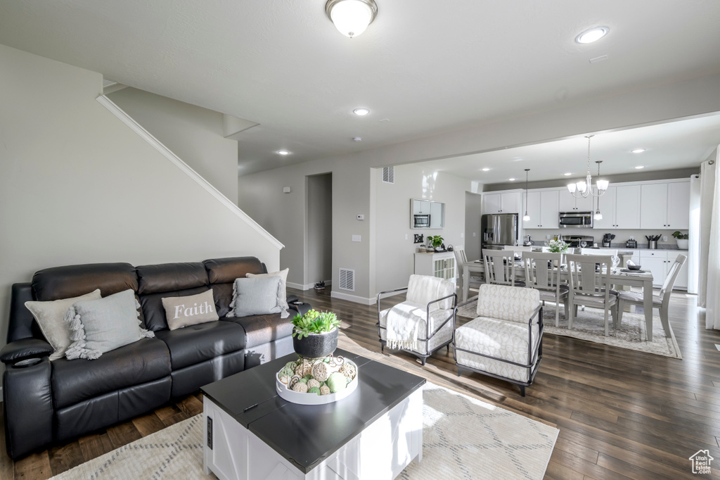 Living area with recessed lighting, dark wood-style flooring, a chandelier, stairs, and baseboards