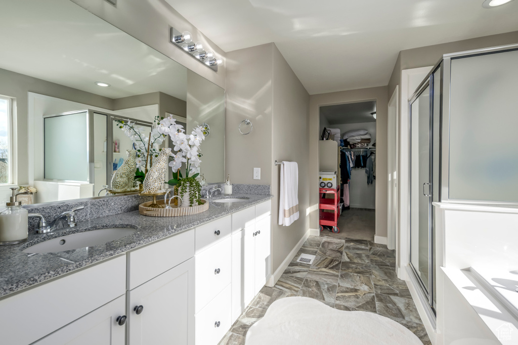 Full bath featuring a shower stall, double vanity, baseboards, a walk in closet, and marble finish flooring