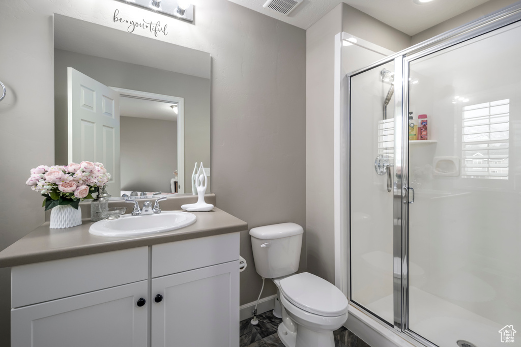 Bathroom with vanity, a shower stall, toilet, marble finish flooring, and baseboards