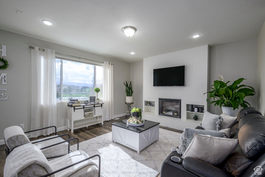 Living room with light wood-type flooring, a fireplace, recessed lighting, and baseboards