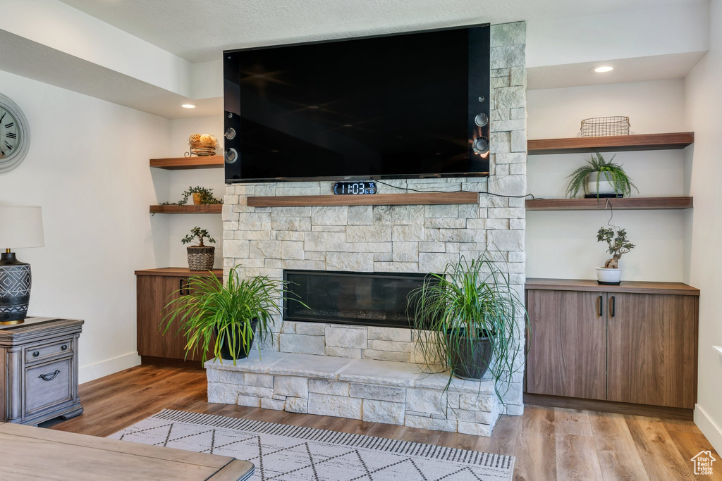 Unfurnished living room with wood finished floors and a stone fireplace