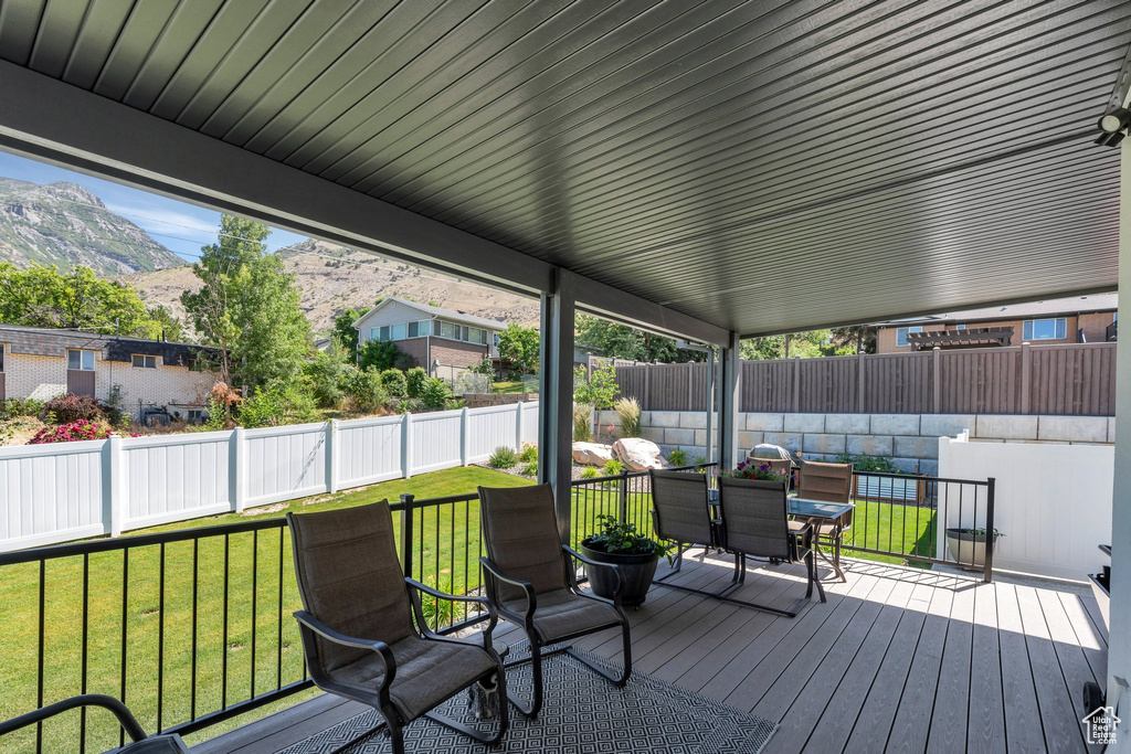 Deck with a mountain view, a fenced backyard, and outdoor dining space