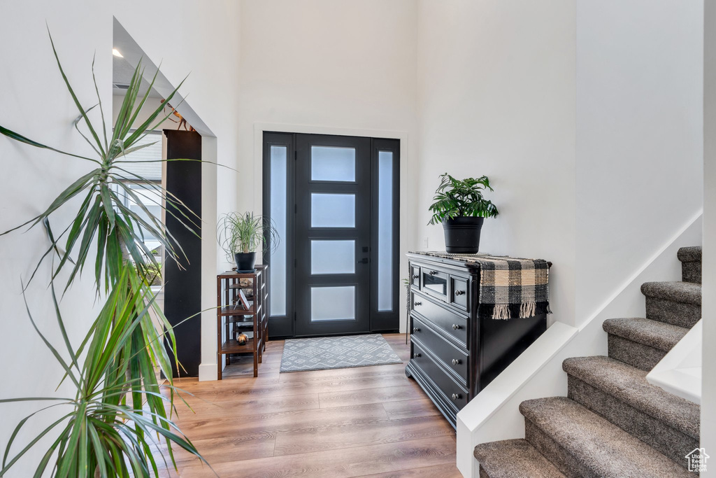 Entryway with light wood-style flooring, stairs, and a high ceiling