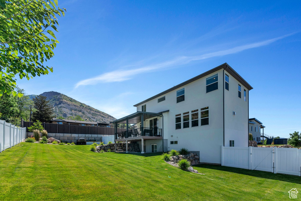 Back of property featuring a fenced backyard, a gate, stucco siding, and a deck with mountain view
