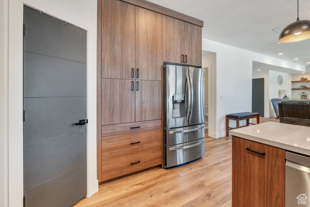 Kitchen featuring stainless steel appliances, light wood-style flooring, light countertops, open floor plan, and modern cabinets