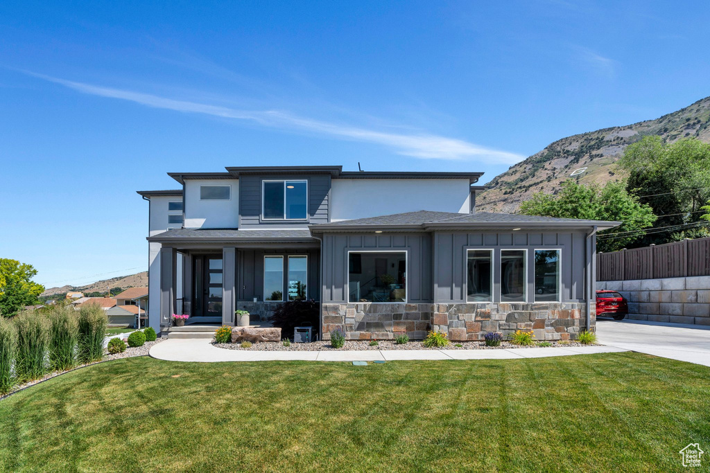 Back of property with board and batten siding, a mountain view, stone siding, and a shingled roof