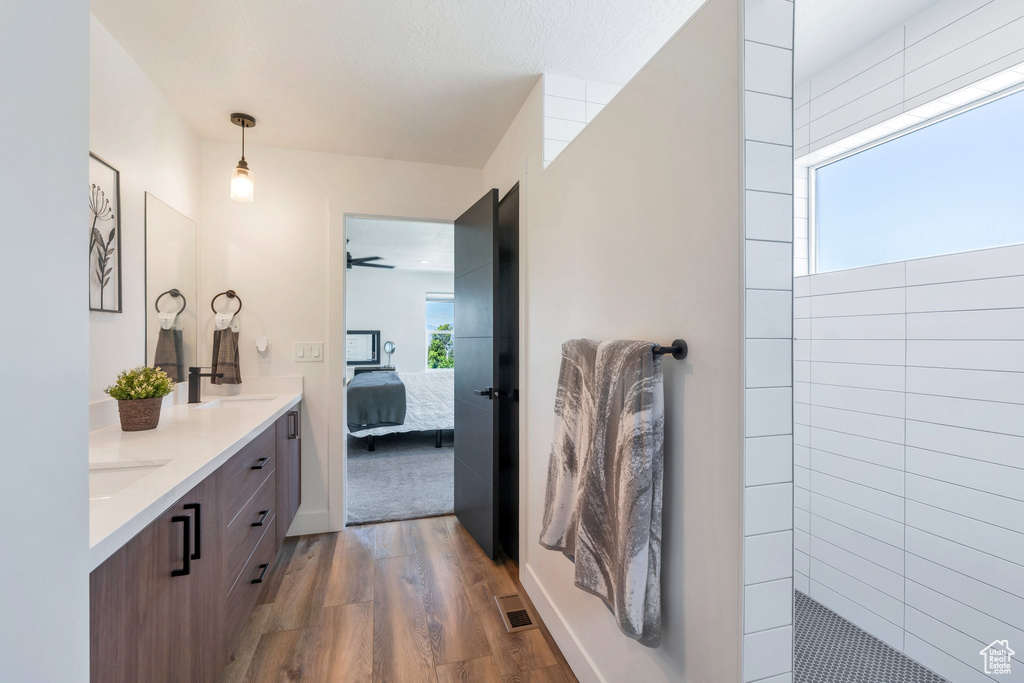 Bathroom featuring wood finished floors, double vanity, connected bathroom, walk in shower, and ceiling fan