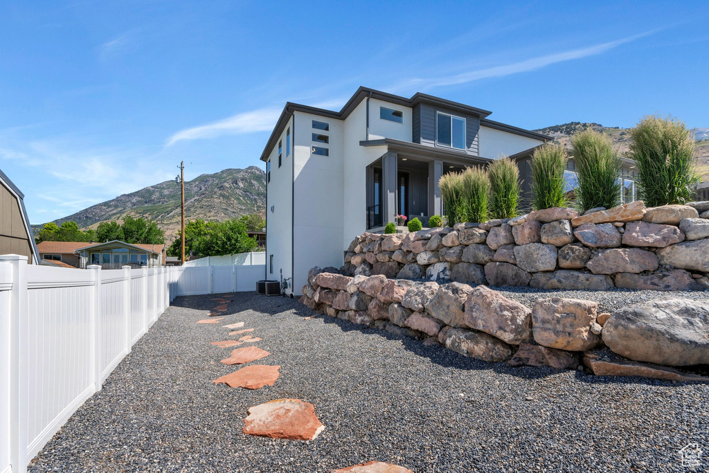 View of side of home with a fenced backyard and a mountain view
