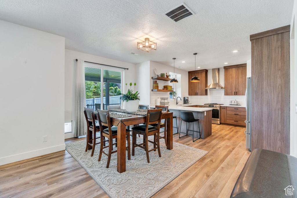 Dining room featuring a textured ceiling, light wood-type flooring, and recessed lighting