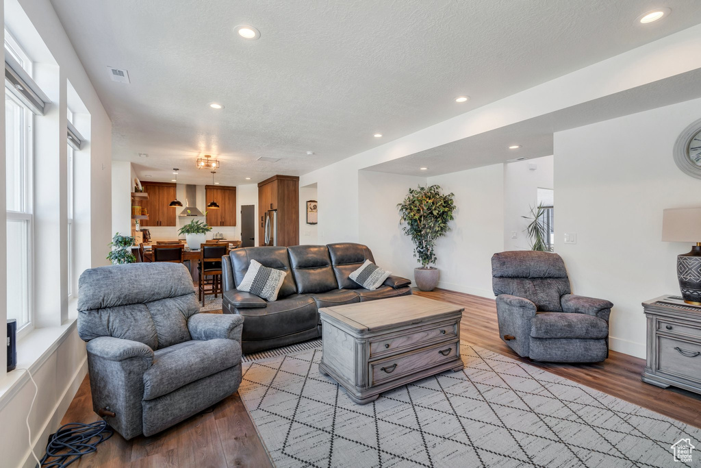 Living area with healthy amount of natural light, light wood-type flooring, recessed lighting, and a textured ceiling