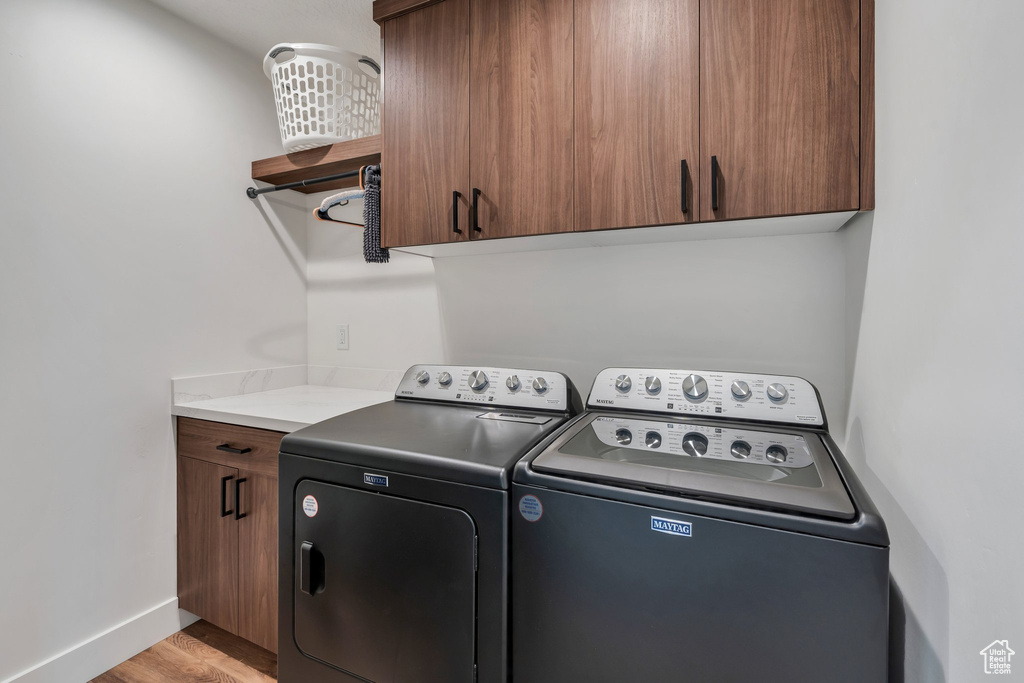 Laundry area featuring cabinet space, washer and clothes dryer, and light wood-style floors