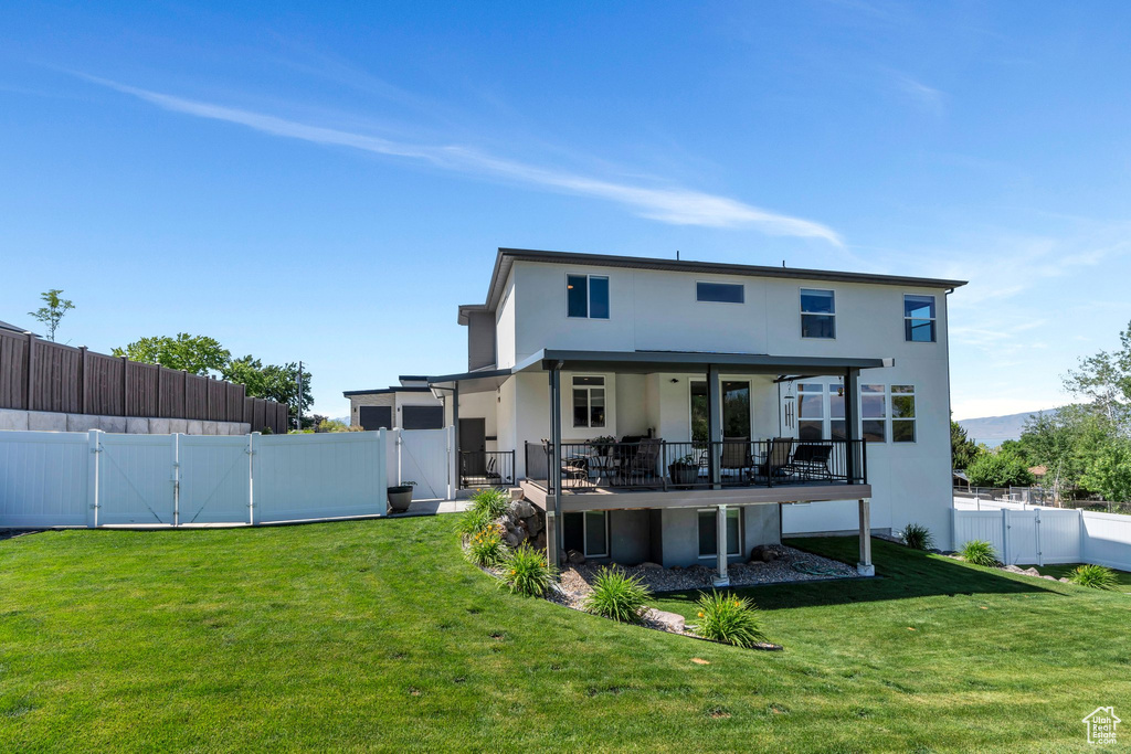 Rear view of property featuring a gate, stucco siding, a fenced backyard, and a deck