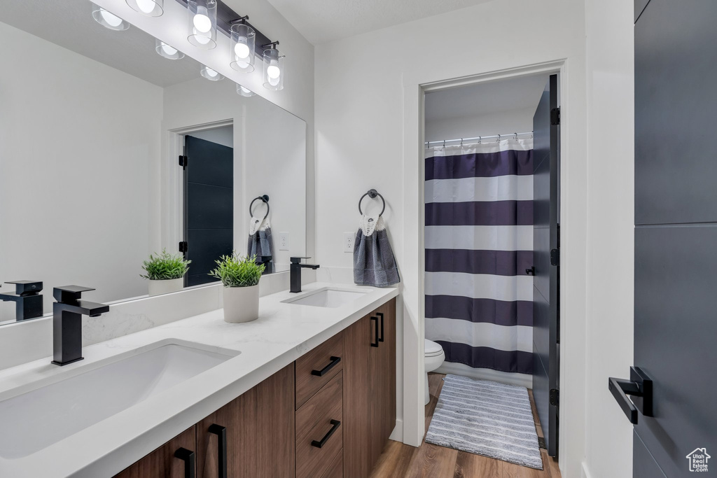 Full bath with wood finished floors, double vanity, and a shower with shower curtain