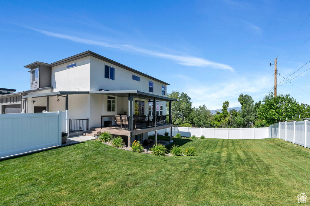 Rear view of property featuring a fenced backyard, a wooden deck, and stucco siding