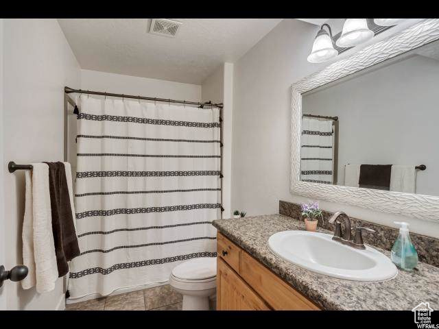 Full bath featuring vanity, toilet, a shower with curtain, and tile patterned floors