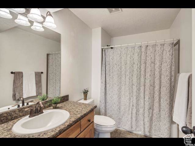 Full bath with vanity, toilet, tile patterned floors, and a shower with shower curtain